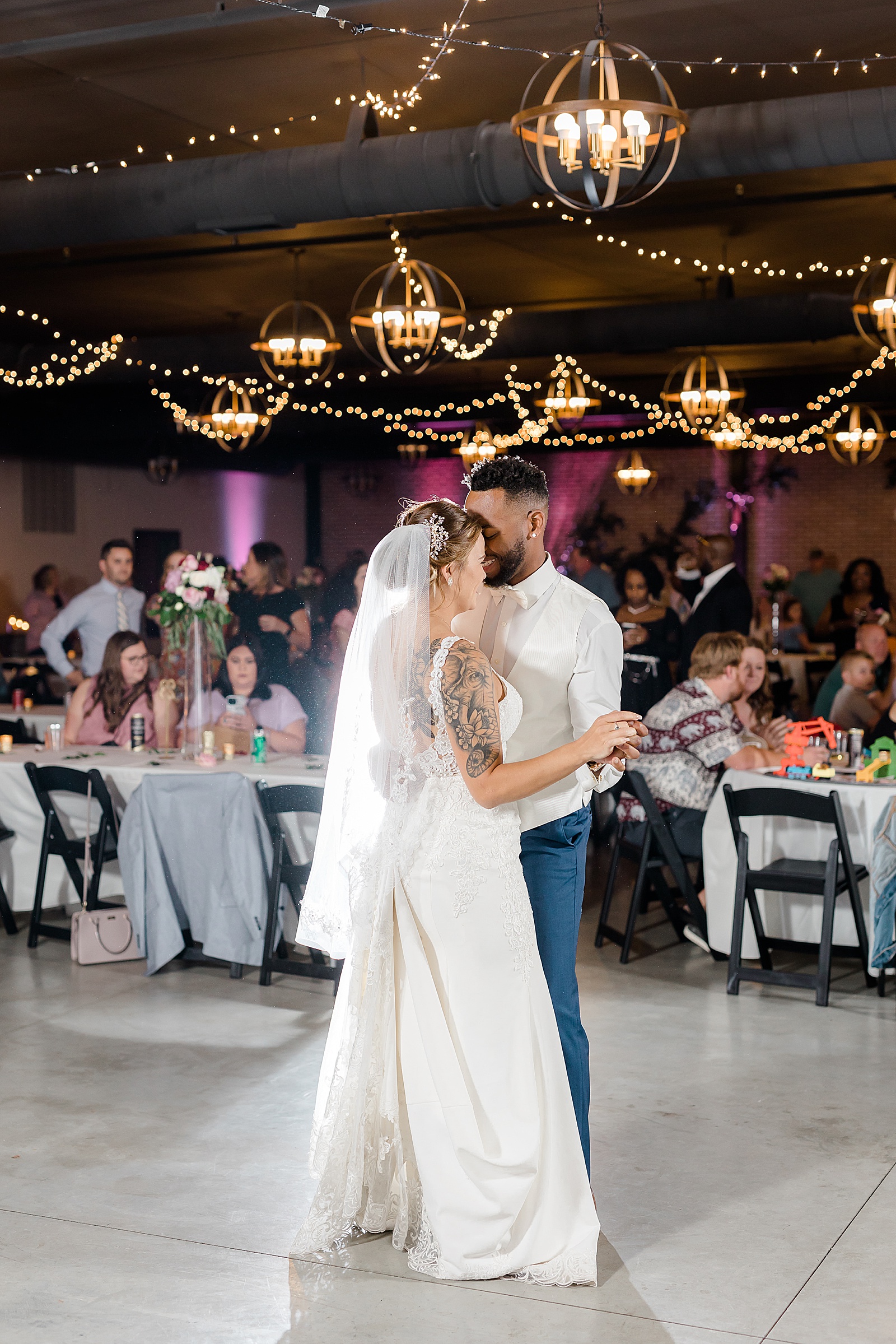 Bride and groom share a first dance in front of their guests at reception 