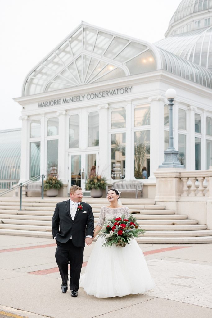Bride and groom laughing and walking in front of a Conservatory building in Minneapolis 