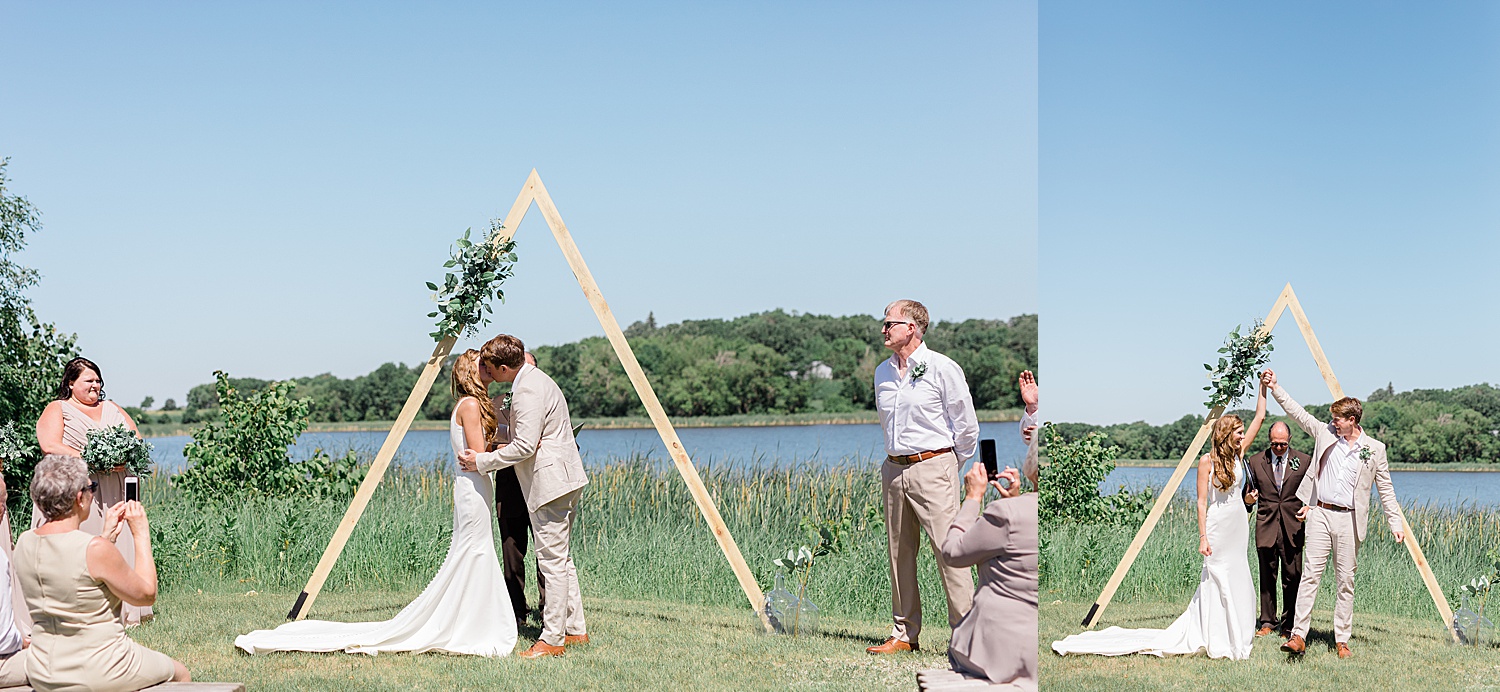 first kiss on wedding day in front of triangle arch with florals during wedding ceremony 
