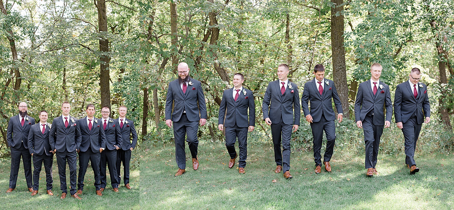 Groom and groomsmen wearing grey suits and red ties walking during wedding party photos 