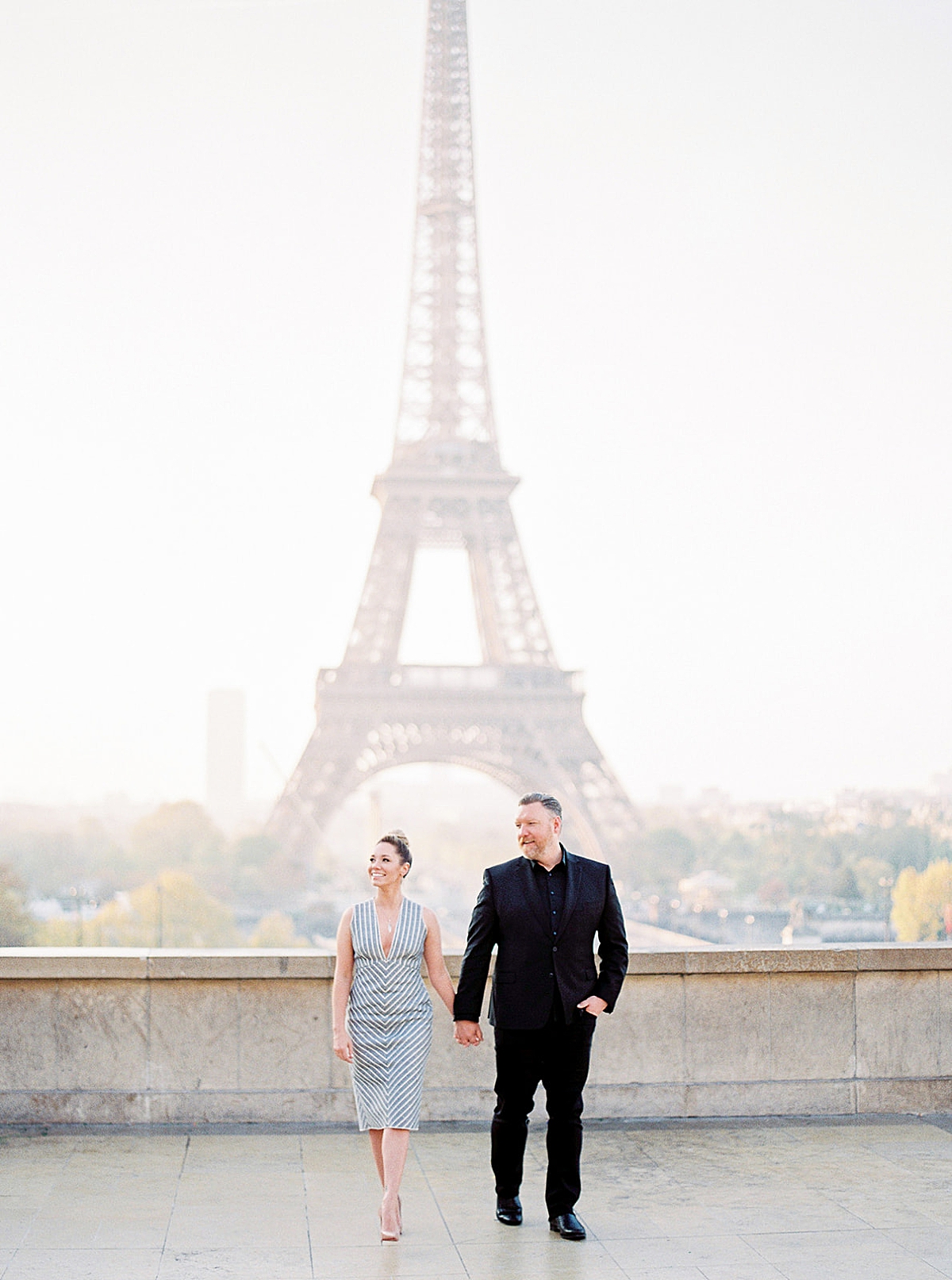 couple walking up the steps at the Eiffel Tower skyline in Paris during honeymoon session 
